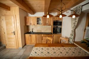 a kitchen with wooden cabinets and a dining table at Chalupa Piecky in Hrabušice