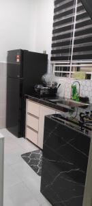 a black and white kitchen with a black counter top at NHP SIDRA Arau in Kampung Kok Kelang