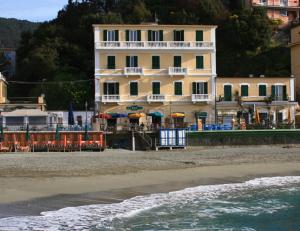 un edificio sulla spiaggia con sedie e ombrelloni di Hotel Baia a Monterosso al Mare