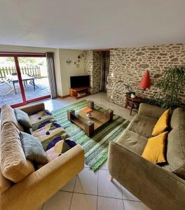 a living room with two couches and a tv at Maison entre Rennes et St-Malo in Saint-Pierre-de-Plesguen