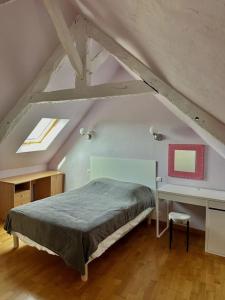 a attic bedroom with a bed and a desk at Maison entre Rennes et St-Malo in Saint-Pierre-de-Plesguen