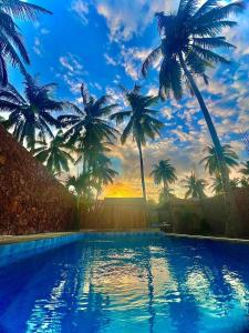 una piscina con palme sullo sfondo di Tata Surf Hostel a Kuta Lombok