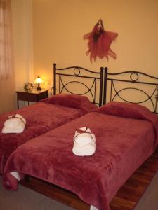 two beds with red sheets and white shoes on them at Chrysoula's Guests in Ioannina