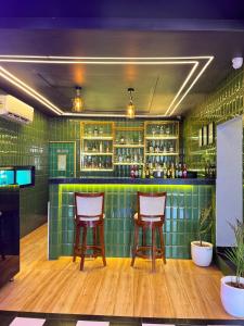 a green tiled bar with two bar stools at AFFLUENCE Hotel in Kharar