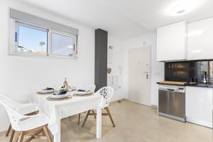 a white kitchen with a white table and chairs at Sungolfbeach El Girasol in Orihuela