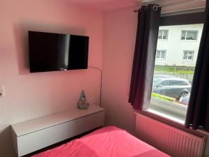 a bedroom with a pink wall with a flat screen tv at Ferienwohnung in Alpirsbach in Alpirsbach