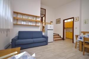 a living room with a blue couch and a kitchen at Villa Negri in Lignano Sabbiadoro