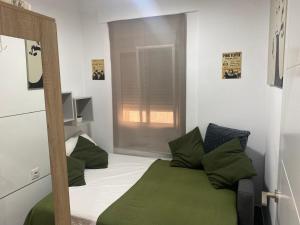 una piccola camera da letto con letto e cuscini verdi di Casa Bella Apartment BY NAMASTE ELITE a Torremolinos