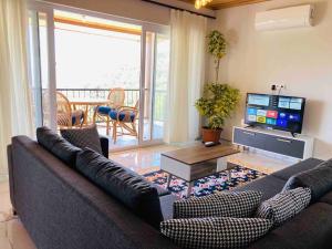 a living room with a couch and a flat screen tv at Magnificent sunset view in Fethiye