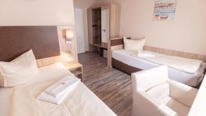 a hotel room with two beds and a desk at Hotel-Restaurant Tüxen in Rendsburg