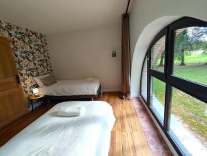 a room with two beds and a large window at grande maison de campagne in Saint-Jean-du-Cardonnay