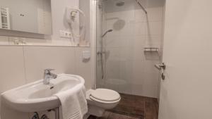 a bathroom with a toilet and a sink and a shower at Hotel-Restaurant Tüxen in Rendsburg +18 photos
