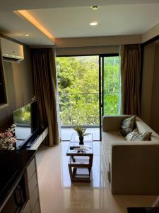 a living room with a couch and a large window at Apartment in Mida Grande Surin in Ban Lum Fuang