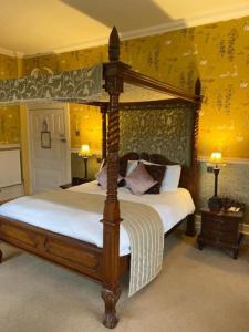 a bedroom with a canopy bed and yellow walls at Langtry Manor Hotel in Bournemouth