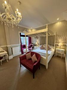 a bedroom with a canopy bed and a red couch at Langtry Manor Hotel in Bournemouth