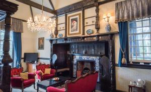 a living room with a fireplace and red chairs at Langtry Manor Hotel in Bournemouth