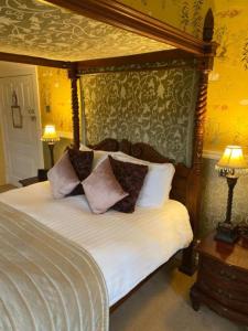 a bedroom with a canopy bed with pillows on it at Langtry Manor Hotel in Bournemouth