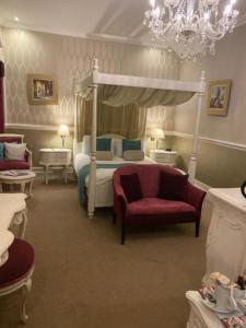 a bedroom with a canopy bed and a chair at Langtry Manor Hotel in Bournemouth