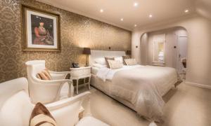 a bedroom with a large white bed and chairs at Langtry Manor Hotel in Bournemouth