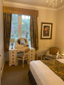 a bedroom with a bed and a desk and a mirror at Langtry Manor Hotel in Bournemouth