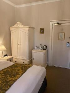 a bedroom with a bed and a cupboard and a bed sidx sidx sidx at Langtry Manor Hotel in Bournemouth