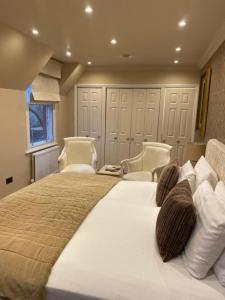 a bedroom with a large bed with two chairs at Langtry Manor Hotel in Bournemouth