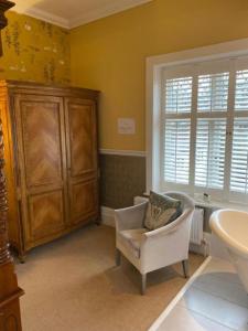 a bathroom with a chair and a sink and a cabinet at Langtry Manor Hotel in Bournemouth