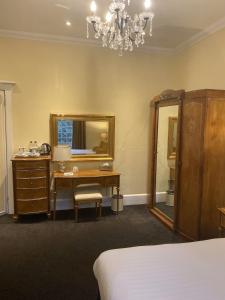 a bedroom with a desk and a mirror at Langtry Manor Hotel in Bournemouth