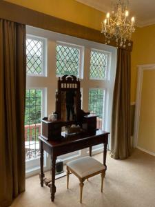 a piano in a room with a chandelier and windows at Langtry Manor Hotel in Bournemouth