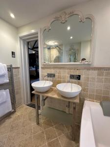 a bathroom with two sinks and a large mirror at Langtry Manor Hotel in Bournemouth