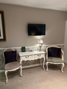 a room with two chairs and a desk with a television at Langtry Manor Hotel in Bournemouth