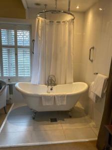 a white bath tub in a bathroom with a shower at Langtry Manor Hotel in Bournemouth