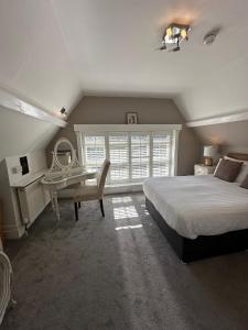 a bedroom with a bed and a desk and a window at Langtry Manor Hotel in Bournemouth