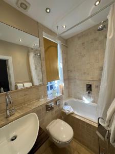 a bathroom with a tub and a sink and a toilet at Langtry Manor Hotel in Bournemouth