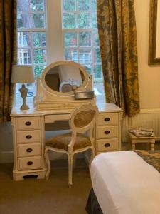 a bedroom with a desk with a mirror and a bed at Langtry Manor Hotel in Bournemouth