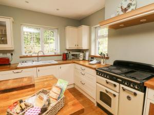 a kitchen with white cabinets and a stove top oven at Nattaden Fourwinds in Okehampton