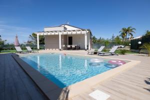 a swimming pool with chairs and a gazebo at Villa Giada in Campofelice di Roccella