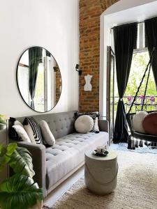 een woonkamer met een bank en een spiegel bij Hola Apartamenty Rewolucji 1905r in Łódź