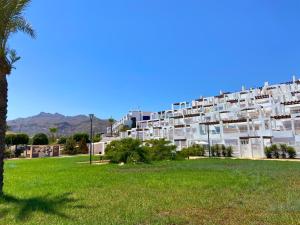 莫哈卡尔Mojacar 1ª linea playa vacaciones的一座带有绿色公园的大型白色公寓楼