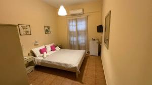 a small bedroom with a bed with pink pillows at romanza rooms in Poulithra