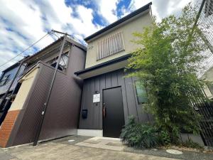 een gebouw met een zwarte deur naast een boom bij Bisuke House in Kyoto