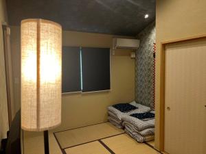 een kamer met 2 bedden in een kamer met een lamp bij Bisuke House in Kyoto
