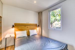 a bedroom with a bed and a window at Mobilhome 6 pers au Castellas in Mèze +21 photos