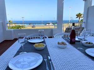 a table with plates and wine glasses and a view of the beach at Mojacar 1ª linea playa vacaciones in Mojácar