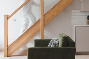 a green chair in a living room with a staircase at Museum Apartments in Edinburgh