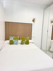 a bedroom with a white bed with green pillows at The Terrace Canalejas in Alicante
