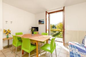 a dining room with a table and green chairs at Budget Village Apartments - Porto Letizia in Porlezza