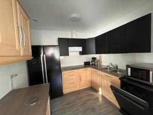 eine Küche mit Holzschränken und einem schwarzen Kühlschrank in der Unterkunft Dream house in Lille + 14 Fotos