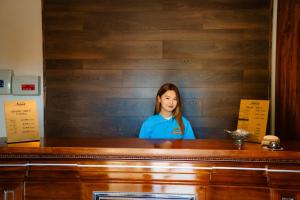 a woman is standing behind a wooden counter at Altair Hotel in Shymkent +215 photos