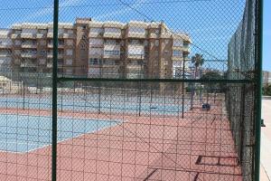 a tennis court with a net in front of a building at Genial 1ª linea de mar Mediterráneo in Torrox